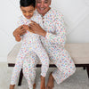 Man and child sitting on a bench wearing matching pajamas with a white background