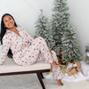 Woman in floral pajamas sitting on a bench with Christmas decorations in the background