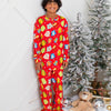 Person wearing red pajamas with colorful patterns, standing next to a decorated Christmas tree.