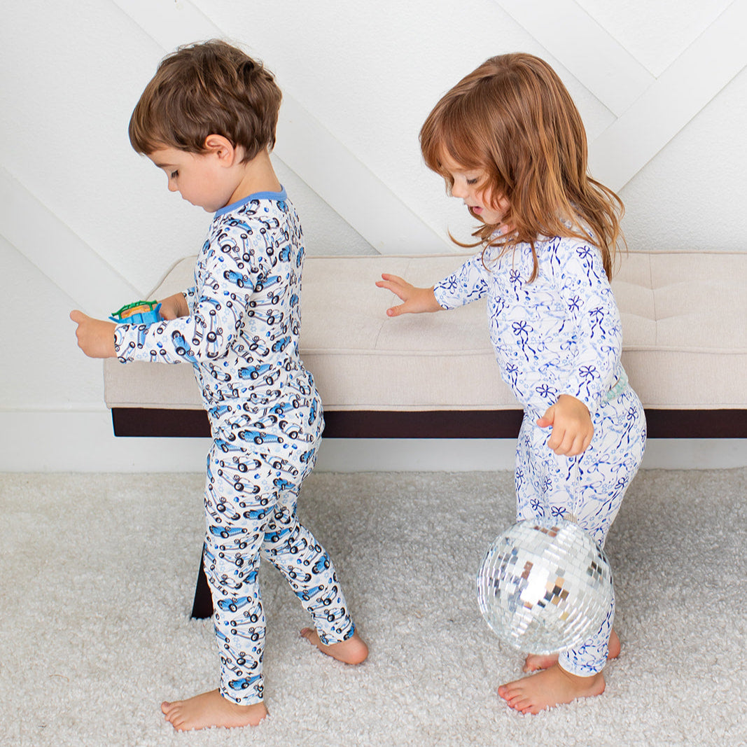 Two children in matching pajamas playing on a carpeted floor.