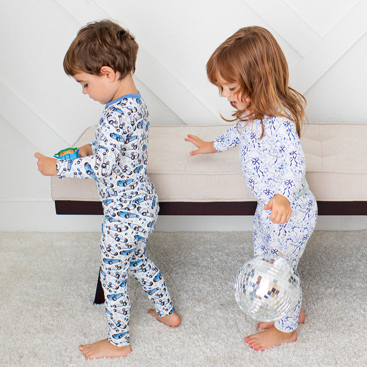 Two children in matching pajamas playing on a carpeted floor.