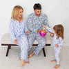 Family in matching pajamas sitting on a bench in a room with a white wall.