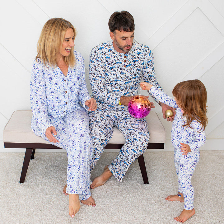 Family in matching pajamas sitting on a bench in a room with a white wall.