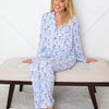 Woman wearing blue floral pajamas sitting on a white bench.
