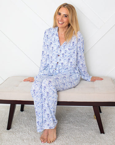Woman wearing blue floral pajamas sitting on a white bench.