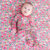 Baby lying on a floral patterned surface wearing a matching outfit.