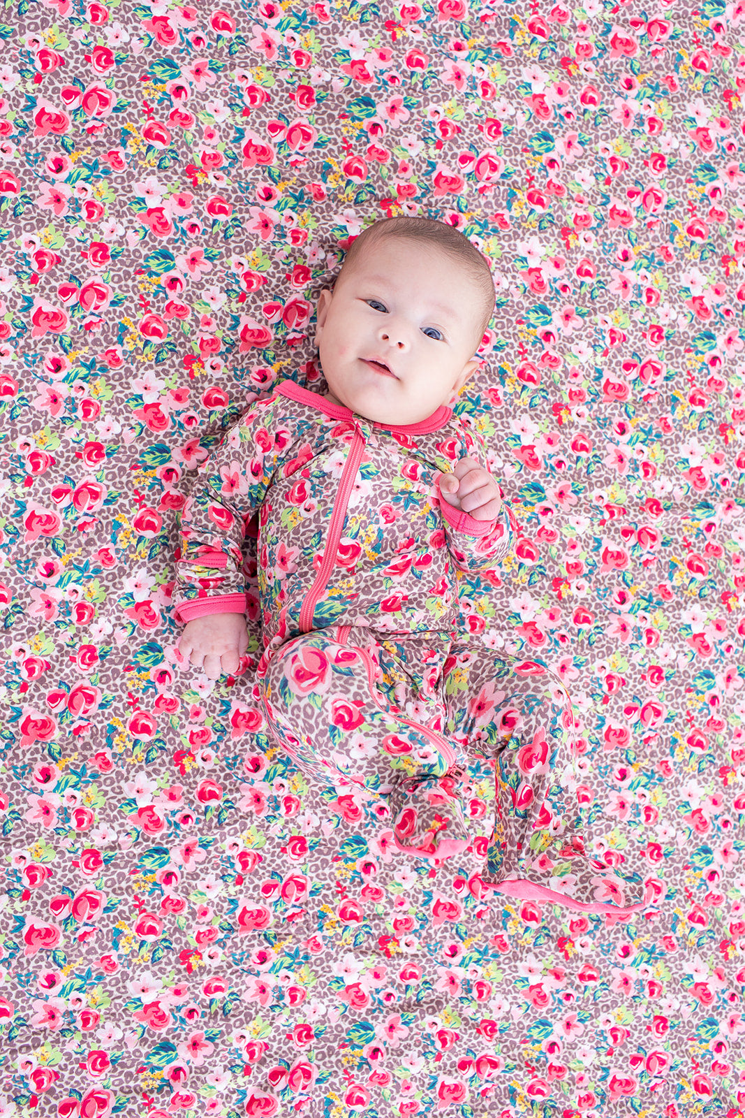 Baby lying on a floral patterned surface wearing a matching outfit.