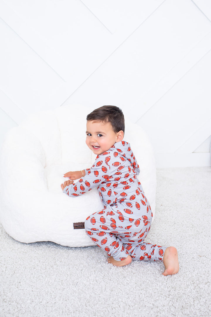Child wearing a red and gray patterned onesie on a white background