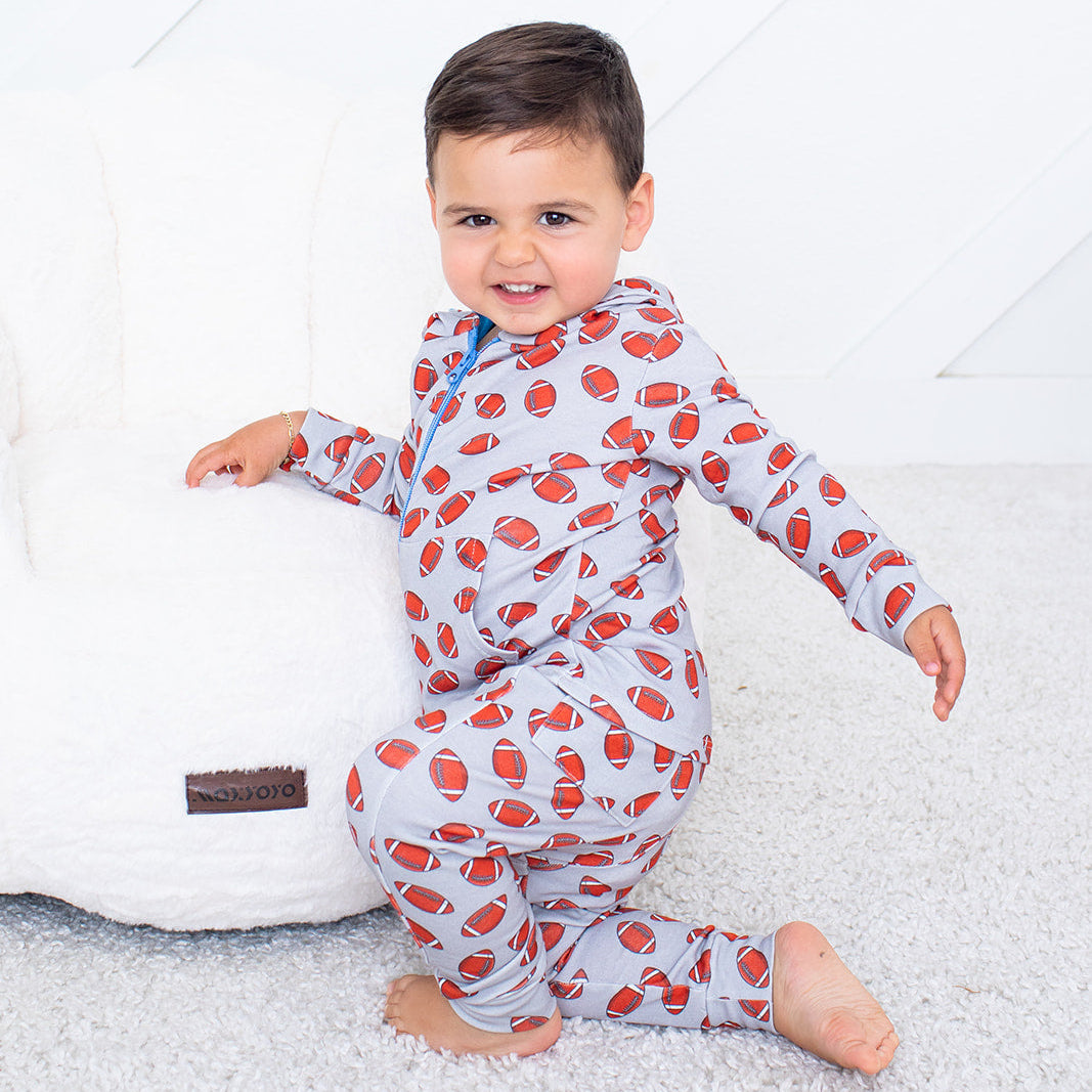 Child wearing a red and white patterned onesie on a white background