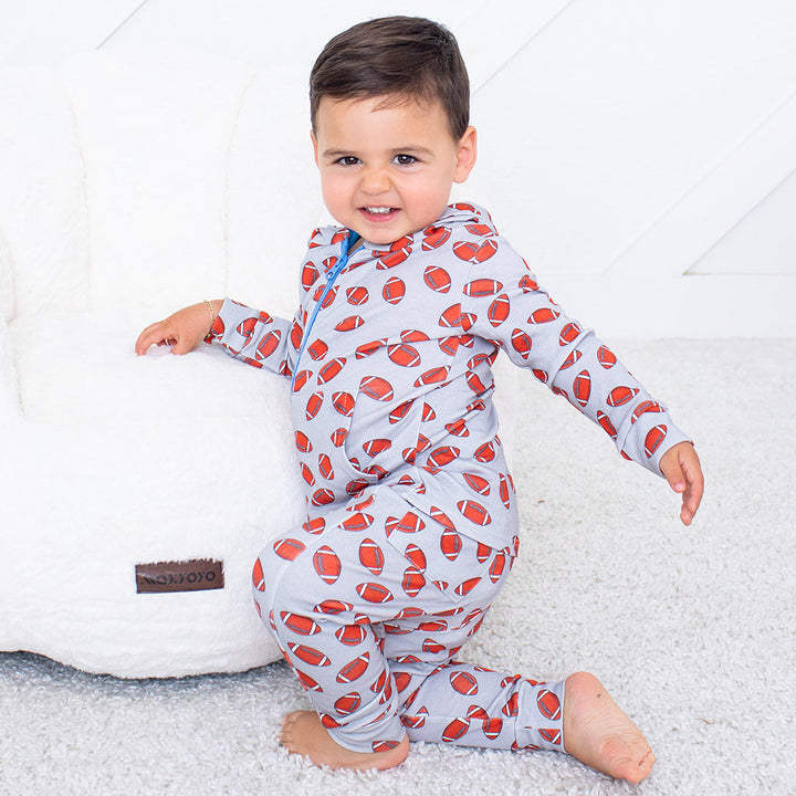 Child wearing a red and white patterned onesie on a white background