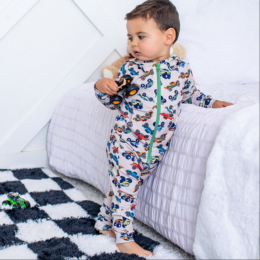 Child in pajamas standing on a checkered rug with a white wall background