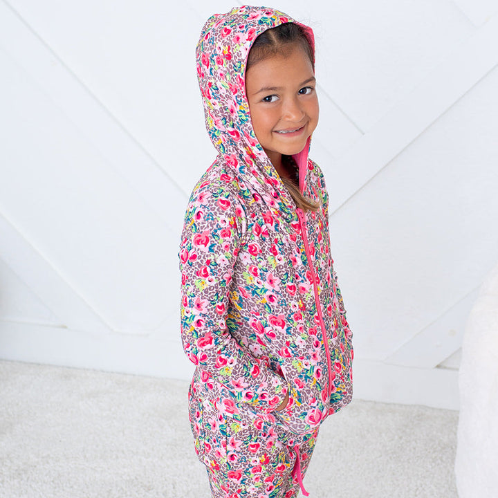 Child wearing a colorful floral onesie against a white background