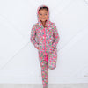 Child wearing a floral onesie with pink zipper on a white floor.