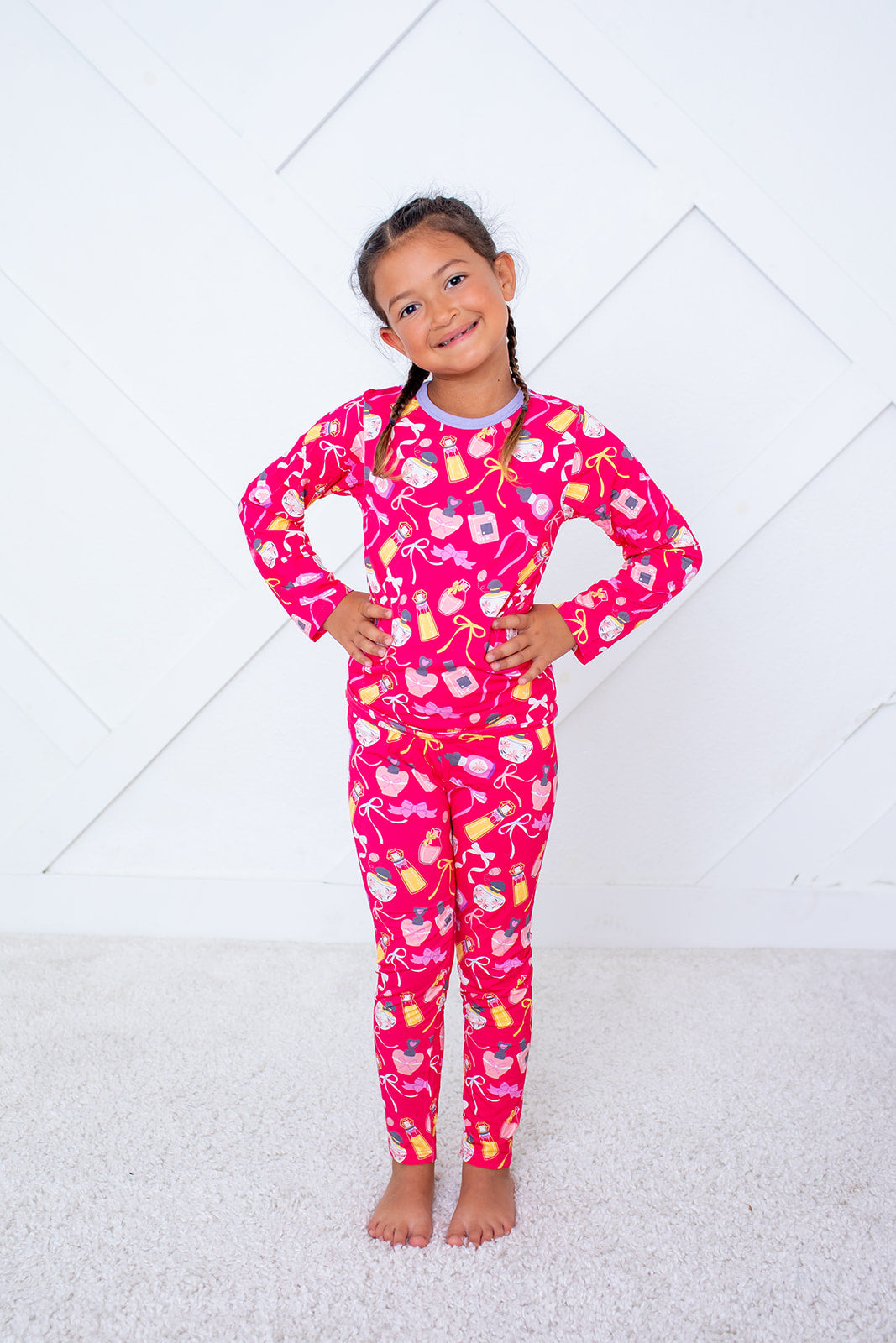 Young girl wearing a pink pajama set with fruit pattern on a white background