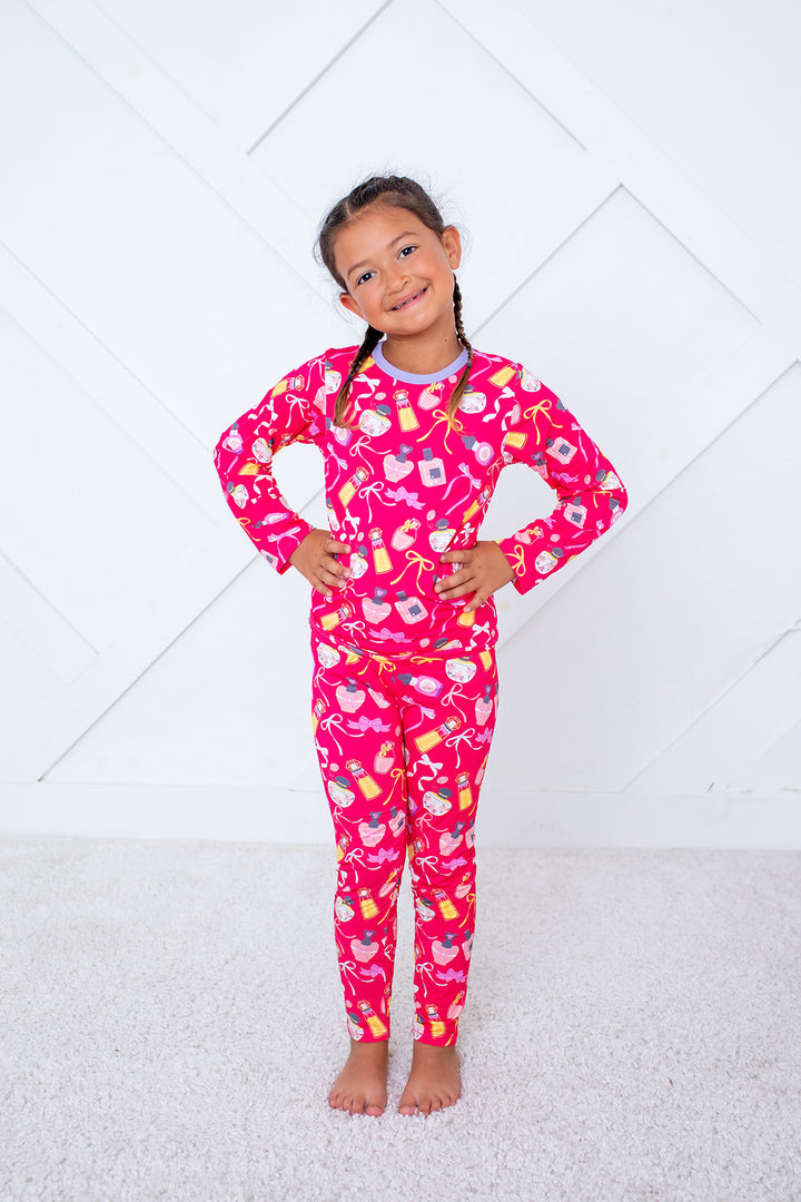 Young girl wearing a pink pajama set with fruit pattern on a white background
