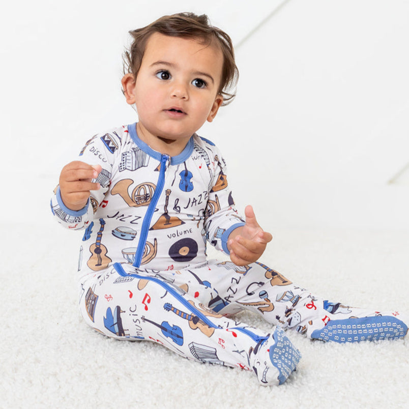 Baby wearing a colorful onesie with cartoon characters on a white background