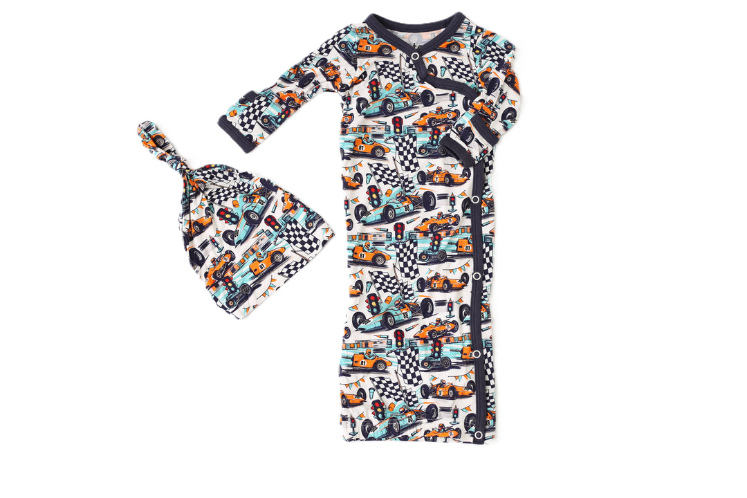 Children's outfit with long-sleeve shirt and hat featuring car and checkered pattern on a white background