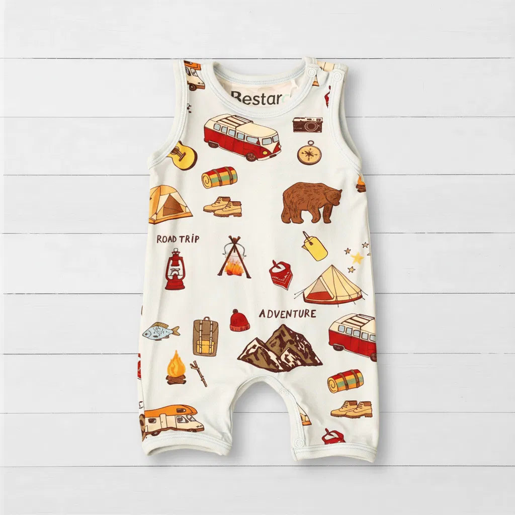 Baby romper with adventure-themed graphics on a wooden surface