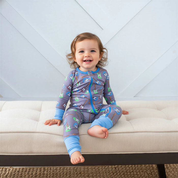 Child wearing a gray and blue pajama set with airplane design on a beige couch.