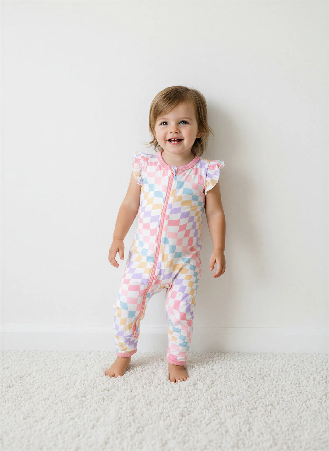 Child wearing a colorful patterned onesie on a white background