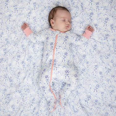 Newborn baby wrapped in a floral blanket with pink accents on a white background