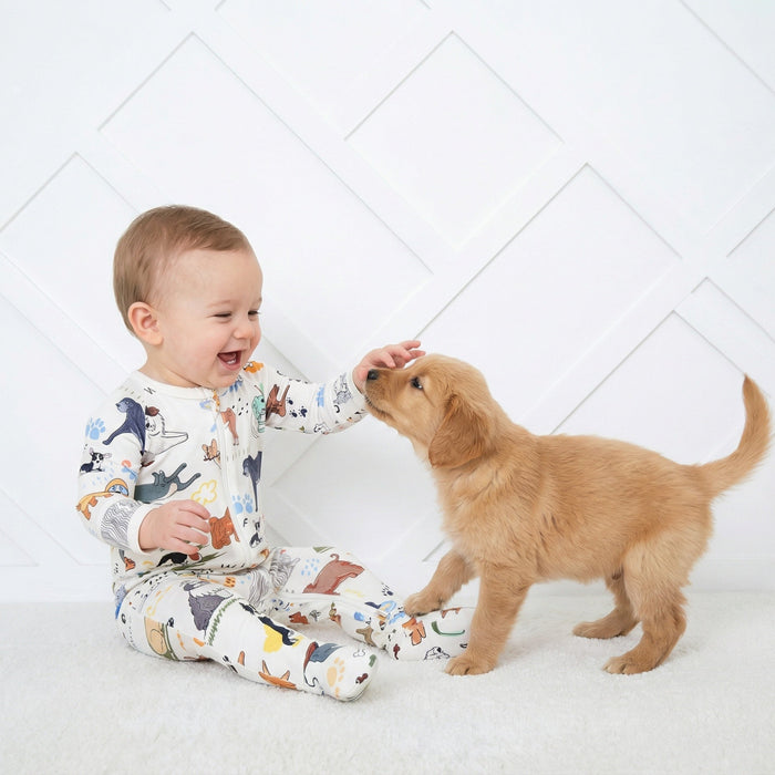 Child in pajamas interacting with a puppy on a white floor.