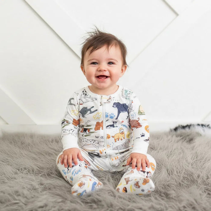 Baby wearing a onesie with animal print sitting on a fluffy surface.