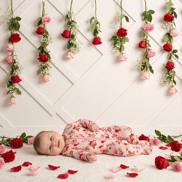 Baby lying on a white floor with floral decorations and rose petals.