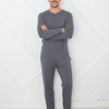 Man wearing gray long-sleeve top and pants standing against a white geometric-patterned wall.