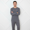 Man wearing gray pajamas standing against a white geometric-patterned wall.